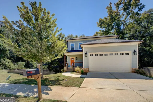 a view of a white house with a small yard and large tree