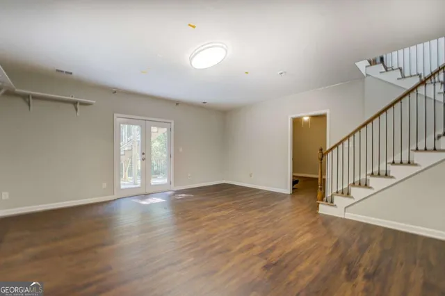 a view of an empty room with wooden floor and stairs