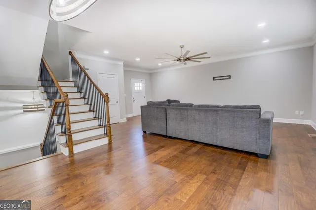 a view of an empty room with wooden floor and stairs