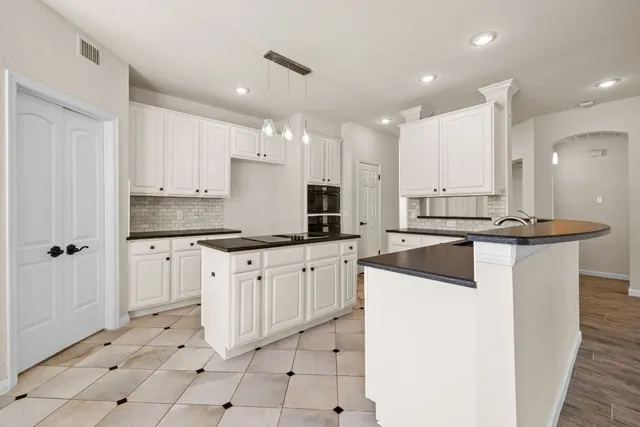 a kitchen with kitchen island granite countertop a sink a stove a counter top space and cabinets