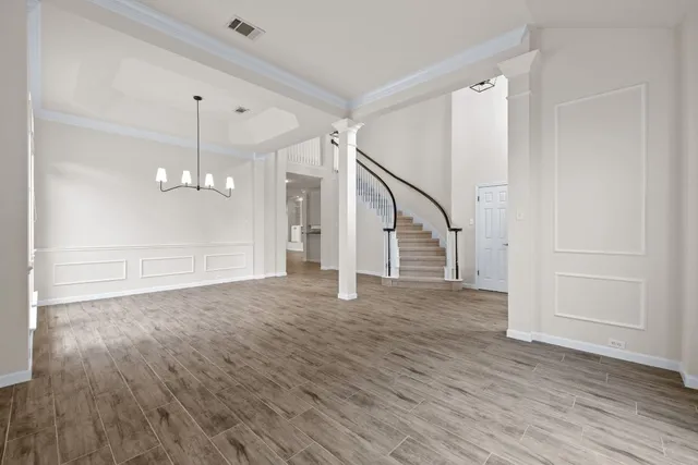a view of empty room with wooden floor and staircase