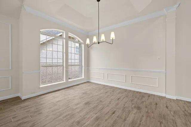 a view of an empty room with wooden floor and fan
