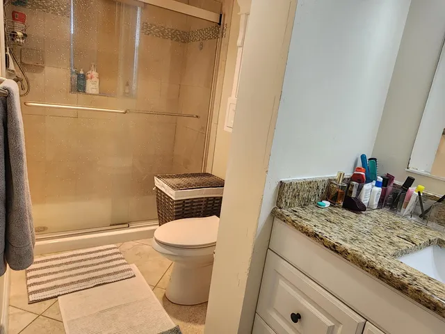 a bathroom with a granite countertop sink toilet and shower