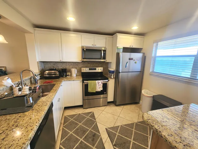 a kitchen with granite countertop a refrigerator and a sink