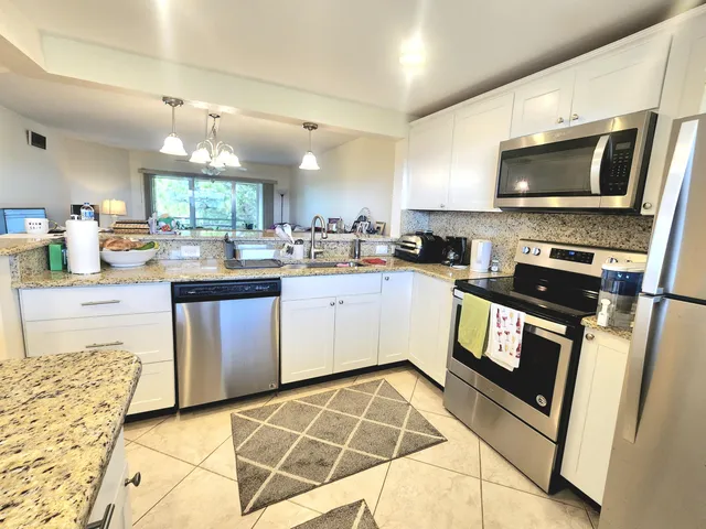 a kitchen with granite countertop a stove top oven and cabinets