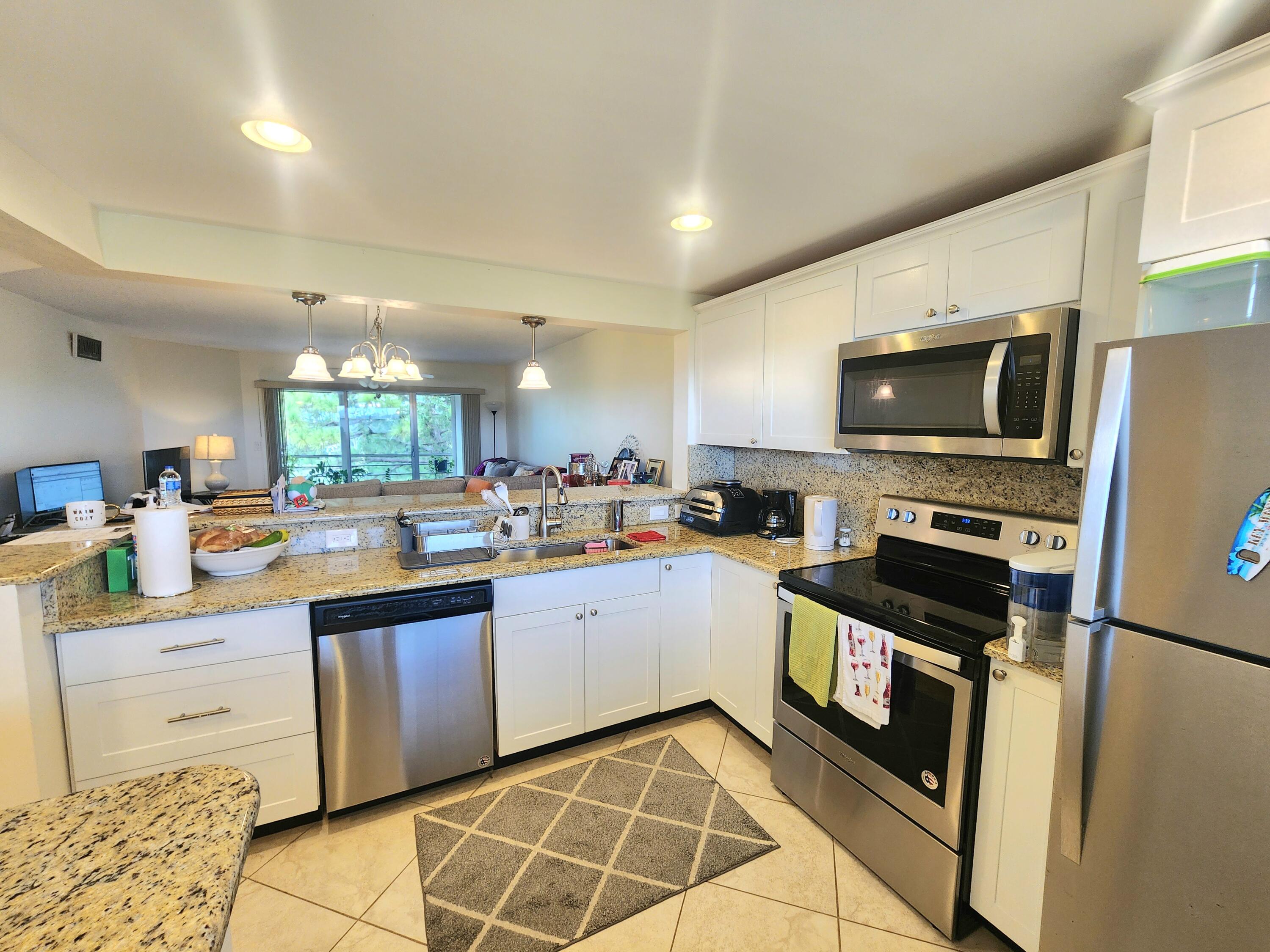 3755 Via Poinciana, Unit 607 Lake Worth, FL 33467 - Photo 6 of 19 a kitchen with stainless steel appliances a stove sink microwave and cabinets