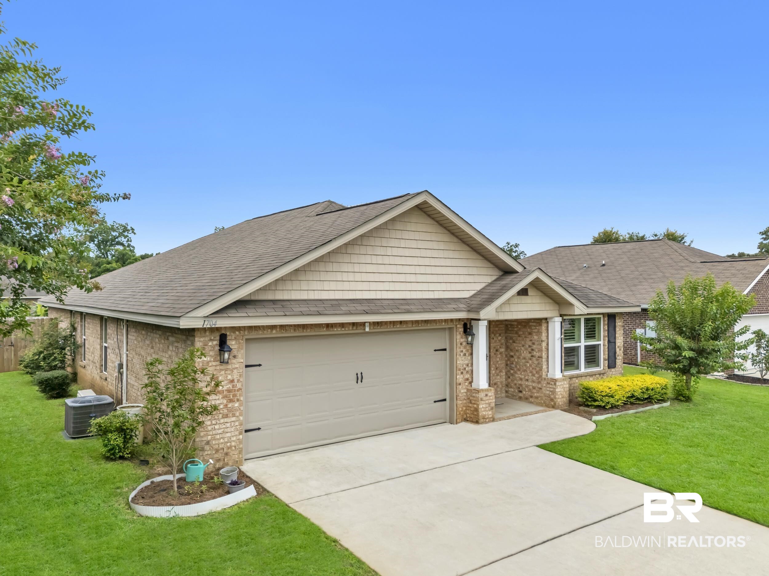 1704 Abbey Loop Foley, AL 36535 - Photo 4 of 38 Brick and siding exterior featuring a two-car garage, concrete driveway, and established landscaping