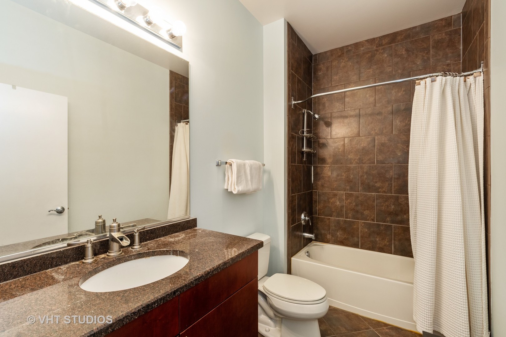 756 West 14th Street, Unit 102 Chicago, IL 60607 - Photo 7 of 10 a bathroom with a granite countertop sink toilet and shower