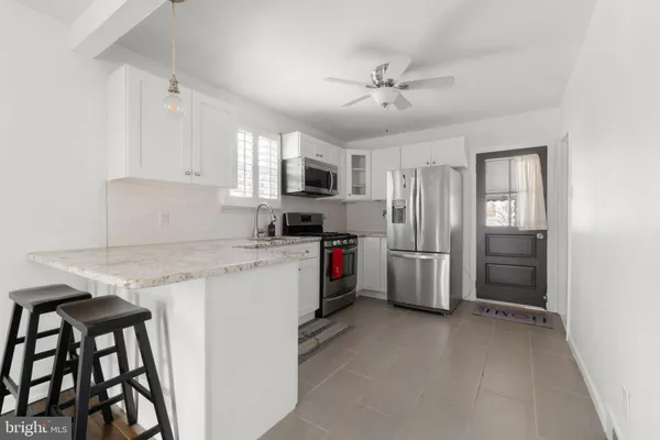 a kitchen with granite countertop a refrigerator a sink a stove and cabinets