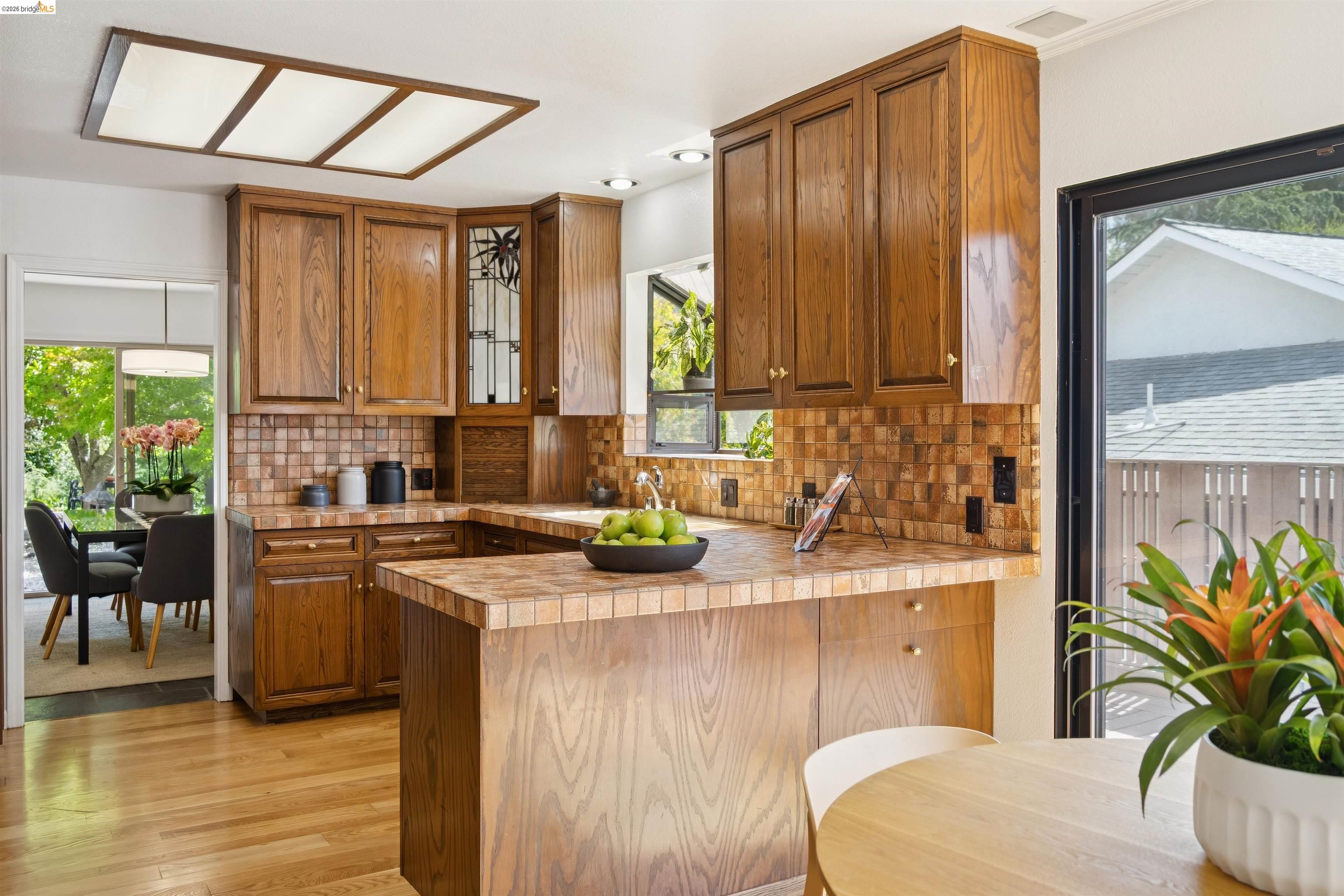 7 Jo Lin Court El Sobrante, CA 94803 - Photo 50 of 99 U-shaped kitchen featuring wood cabinetry, tile countertops, and a mosaic tile backsplash