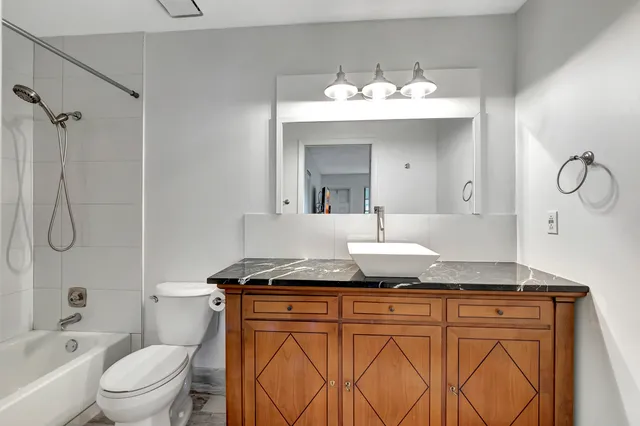 a bathroom with a granite countertop sink vanity mirror and toilet