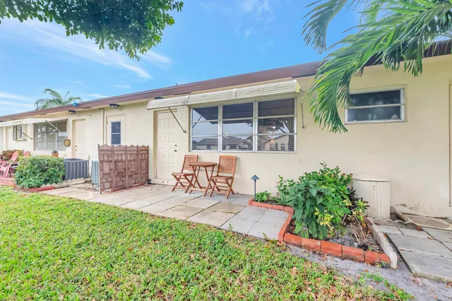 a view of a backyard with table and chairs potted plants and a house