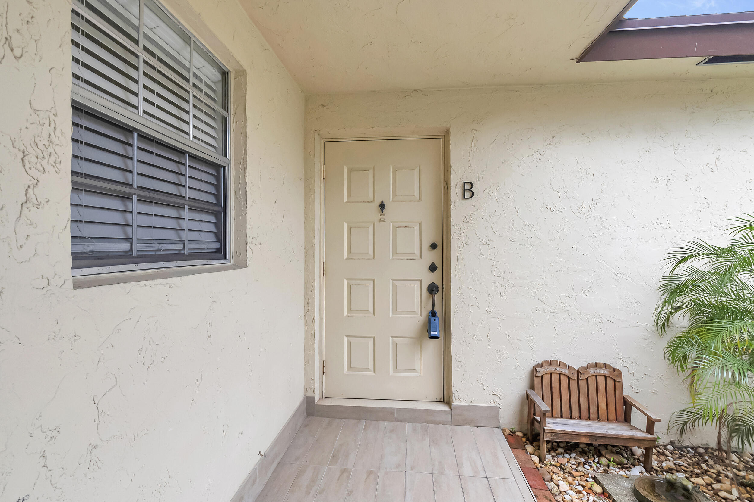 14040 Nesting Way, Unit B Delray Beach, FL 33484 - Photo 4 of 26 a wooden floor with a chair and a potted plant next to a window