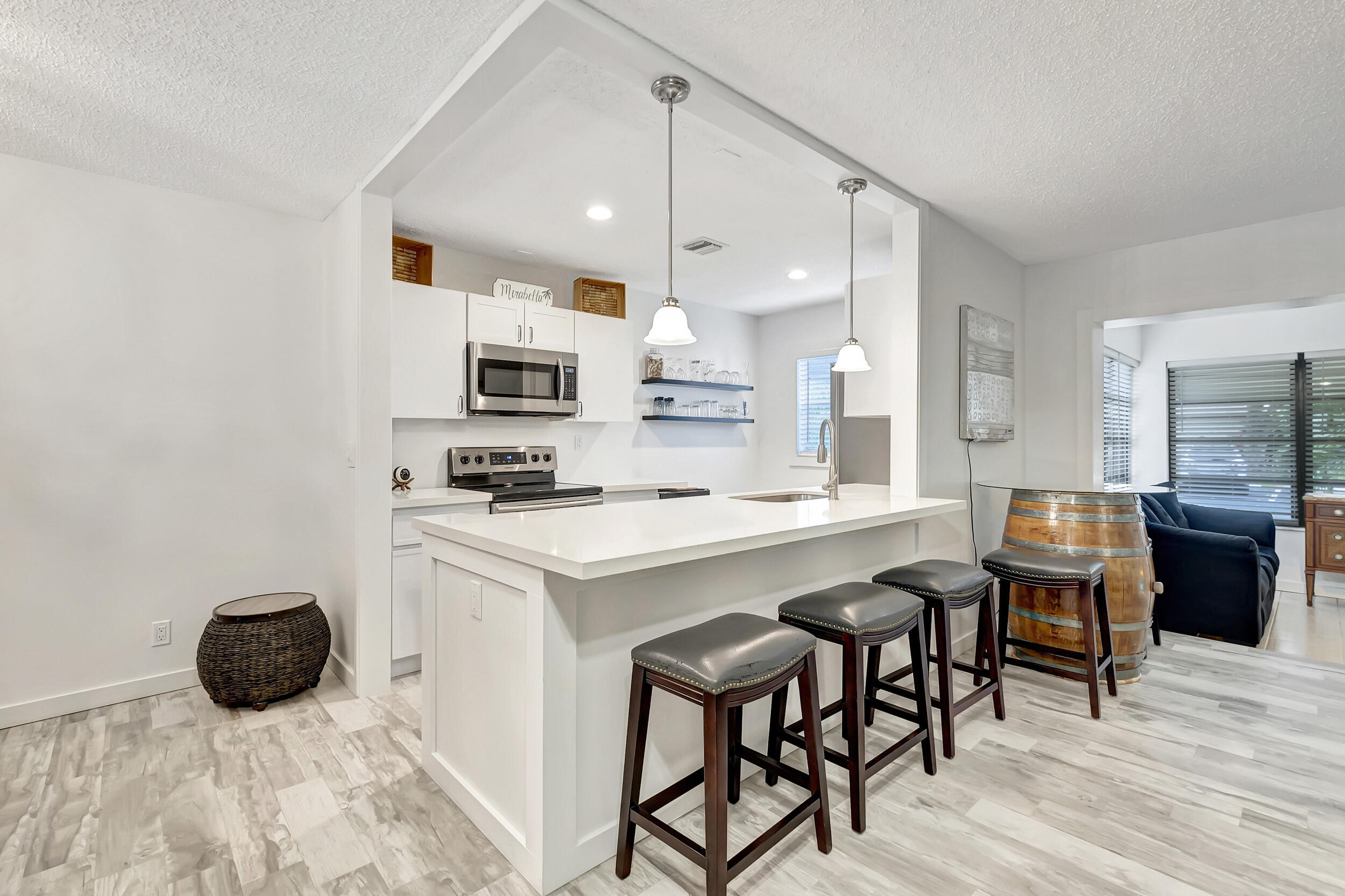 14040 Nesting Way, Unit B Delray Beach, FL 33484 - Photo 5 of 26 a kitchen with a sink a microwave a stove and white cabinets