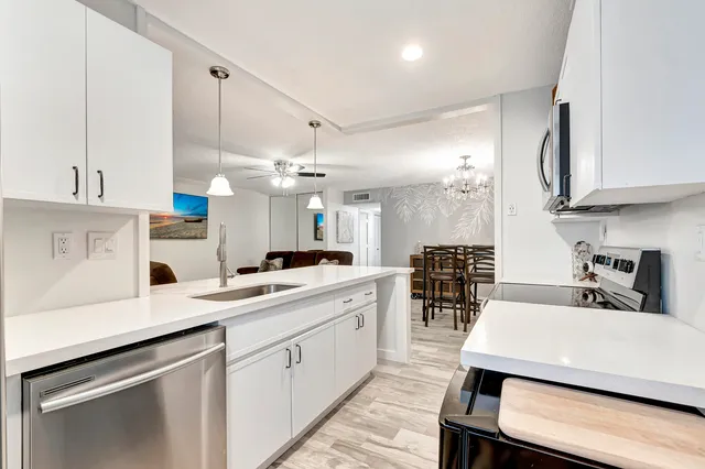 a kitchen with a sink a center island stainless steel appliances and cabinets
