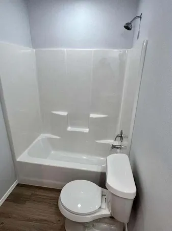 a white toilet sitting next to a bath tub