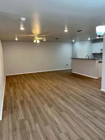 an empty room with kitchen view and wooden floor