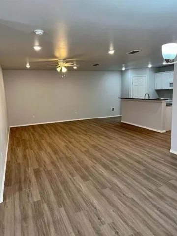 an empty room with kitchen view and wooden floor