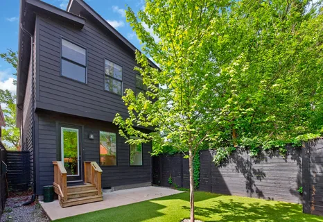 a front view of a house with a garden and trees