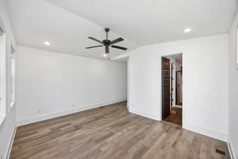 an empty room with wooden floor and a ceiling fan