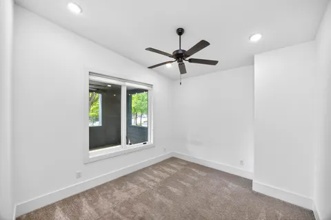 an empty room with a window and a ceiling fan