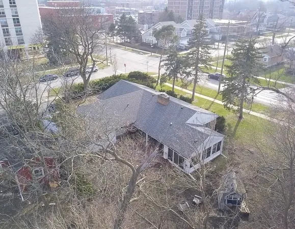 a aerial view of a house with a yard and a large tree