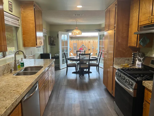 a kitchen with stainless steel appliances granite countertop a stove a sink and a wooden floors