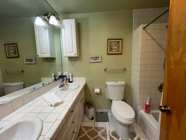 a view of a hallway with wooden floor and a bathroom