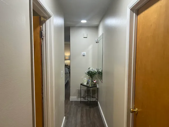 an empty room with wooden floor & hallway