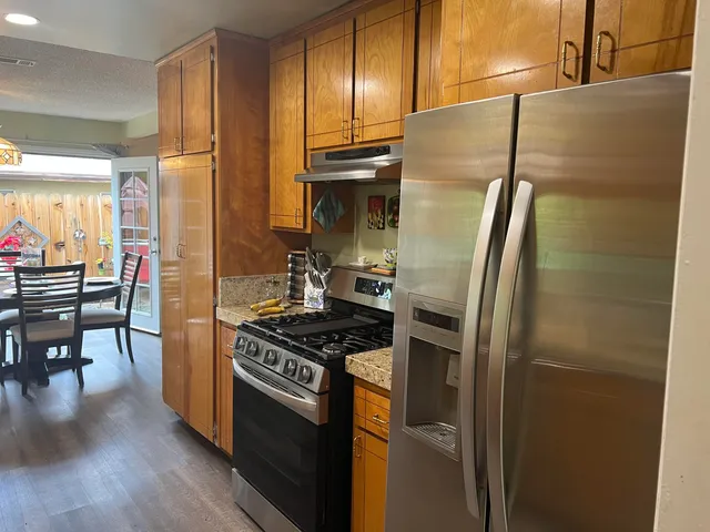 a kitchen with stainless steel appliances a refrigerator and wooden floor