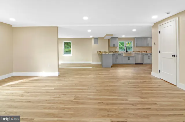 a view of kitchen and empty room with wooden floor