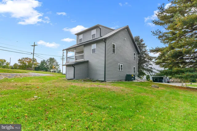 a view of a house with a yard and large tree