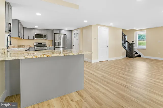 a kitchen with stainless steel appliances granite countertop a refrigerator stove a sink and dishwasher with wooden floor