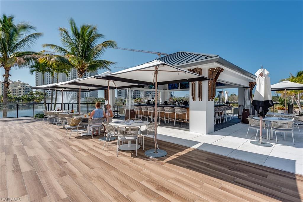 13945 Old Coast Road, Unit 406 Naples, FL 34110 - Photo 46 of 46 a patio with a table and chairs under an umbrella