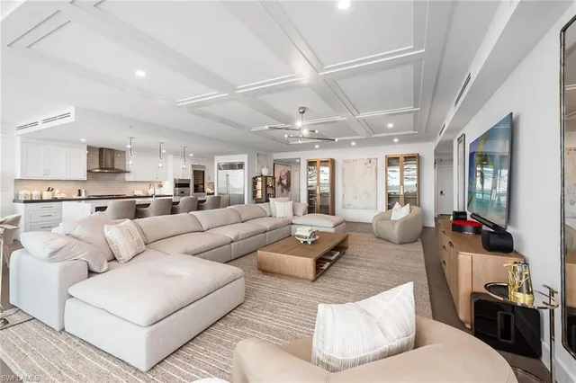 a living room with furniture kitchen view and a wooden floor