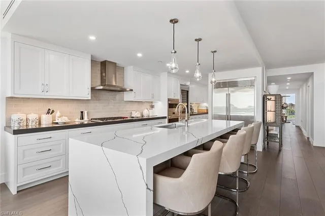 a kitchen with stainless steel appliances kitchen island a table chairs sink and cabinets