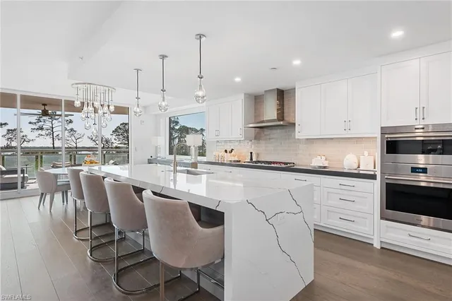 a kitchen with stainless steel appliances granite countertop a stove a sink a microwave a dining table and chairs with wooden floor