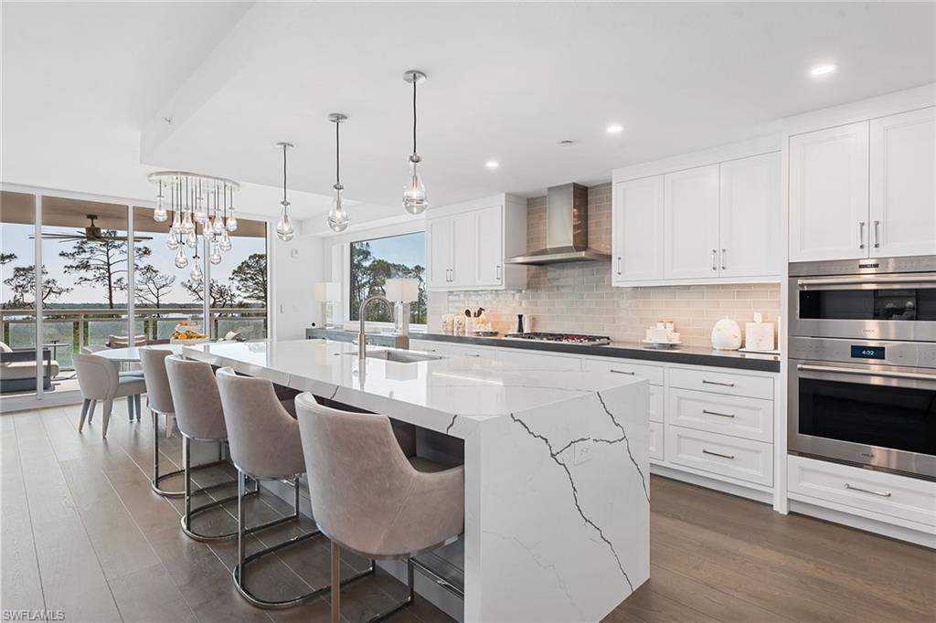 13945 Old Coast Road, Unit 406 Naples, FL 34110 - Photo 7 of 46 a kitchen with stainless steel appliances granite countertop a stove a sink a microwave a dining table and chairs with wooden floor