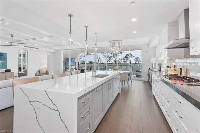 a large white kitchen with kitchen island a stove a sink a faucet and a wooden floor