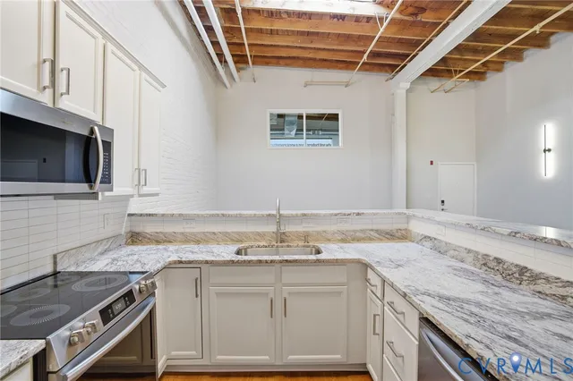 a kitchen with granite countertop a sink stainless steel appliances and cabinets