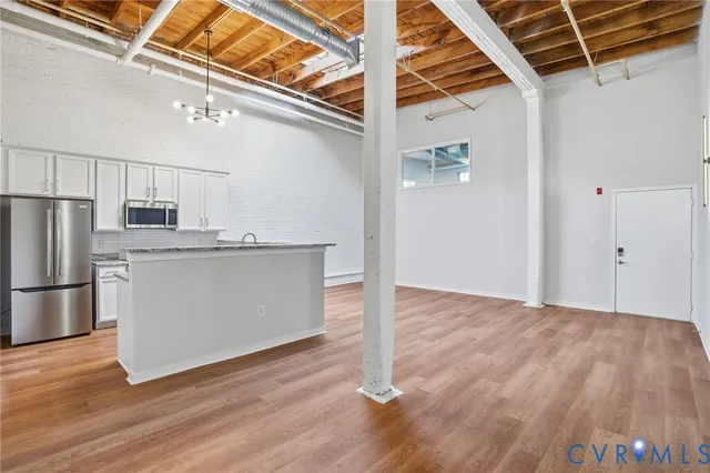 a view of a kitchen with wooden floor electronic appliances and stairs