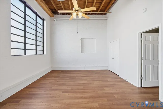 an empty room with wooden floor and windows
