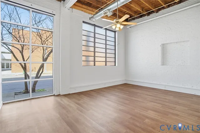 an empty room with wooden floor and windows