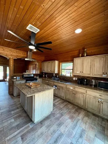 a kitchen with stainless steel appliances granite countertop a sink a stove and a wooden floors