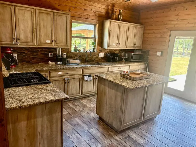 a kitchen with kitchen island granite countertop a sink a counter top space and cabinets