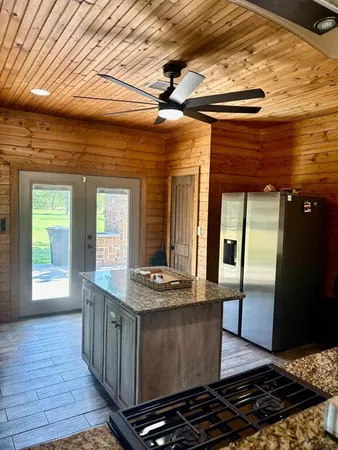 a kitchen with kitchen island granite countertop a stove and a shower