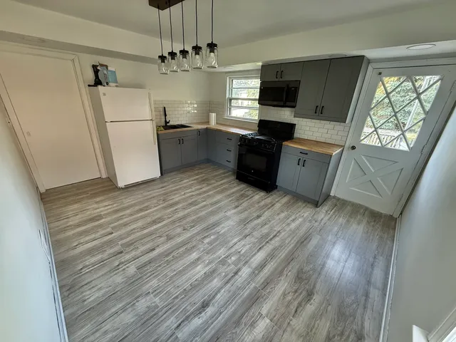 a large kitchen with a refrigerator a stove top oven a sink dishwasher and wooden floor