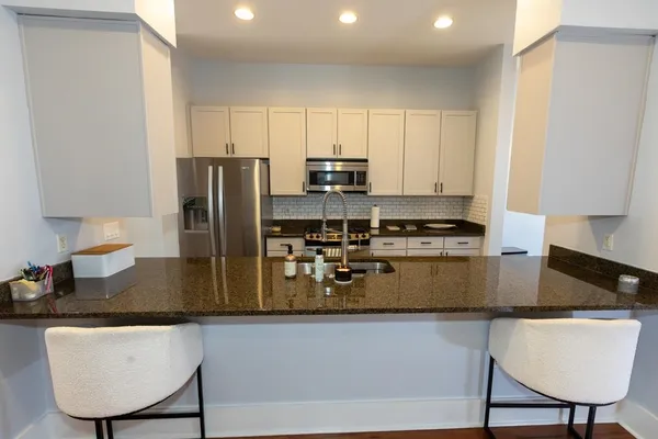 a kitchen with stainless steel appliances granite countertop a stove a refrigerator a sink a stove a dining table and chairs