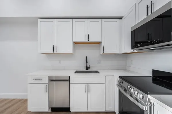 a kitchen with white cabinets stainless steel appliances and sink