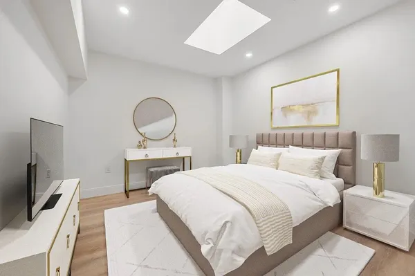 a bedroom with a bed a mirror on dresser and a flat screen tv